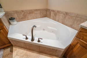 Bathroom featuring tiled tub, tile patterned flooring, and vanity