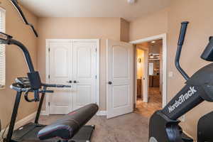 Exercise area with light carpet, a textured ceiling, and ceiling fan