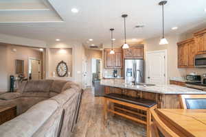 Kitchen with appliances with stainless steel finishes, dark wood-type flooring, sink, pendant lighting, and an island with sink