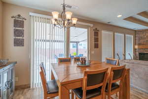 Dining room featuring a stone fireplace, light hardwood / wood-style flooring, and an inviting chandelier