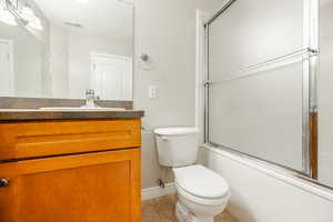 Full bathroom with tile patterned flooring, vanity, toilet, and enclosed tub / shower combo