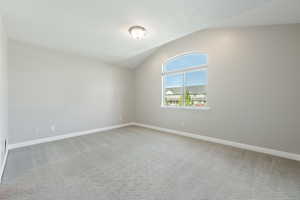 Spare room with carpet flooring, a textured ceiling, and vaulted ceiling