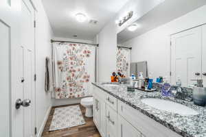 Full bathroom with vanity, hardwood / wood-style flooring, toilet, and shower / bath combo with shower curtain