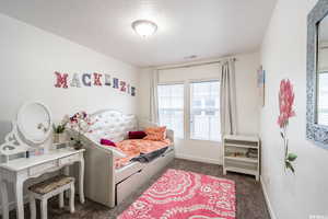 Bedroom featuring dark carpet and a textured ceiling