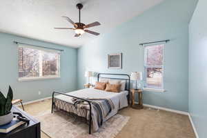 Bedroom with ceiling fan, vaulted ceiling, light carpet, and multiple windows