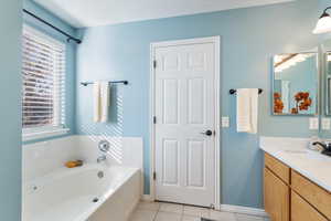 Bathroom featuring tile patterned floors, plenty of natural light, a tub, and vanity