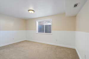 Spare room featuring a textured ceiling and light colored carpet