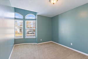 Empty room with carpet floors and a textured ceiling