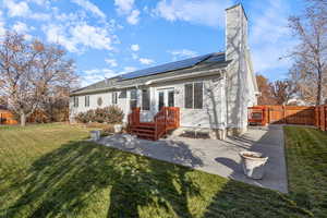 Rear view of property with a patio area, a yard, and solar panels