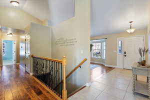 Entrance foyer with light hardwood / wood-style floors and vaulted ceiling