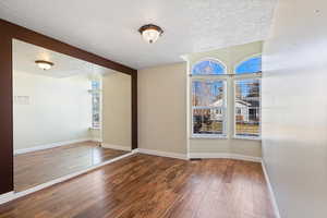 Unfurnished room with a textured ceiling and hardwood / wood-style flooring