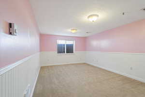 Unfurnished room featuring light colored carpet and a textured ceiling