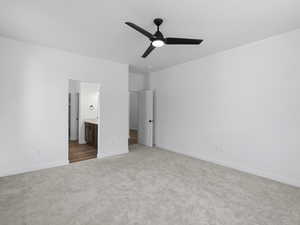 Unfurnished bedroom with ceiling fan, light colored carpet, and connected bathroom