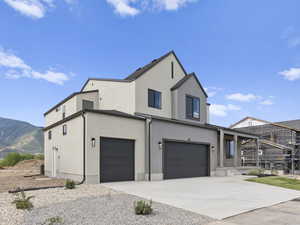 View of front of property featuring a mountain view, glass enclosure, and a garage