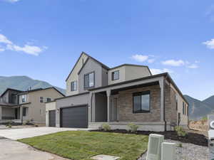 View of front of property with a mountain view, covered porch, a front yard, and a garage