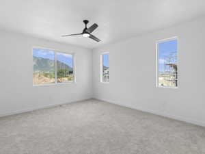 Carpeted spare room with a wealth of natural light and ceiling fan