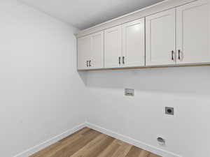 Laundry room featuring electric dryer hookup, cabinets, hookup for a washing machine, and light hardwood / wood-style floors