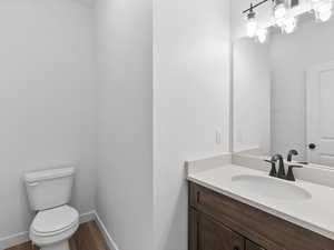 Bathroom with toilet, vanity, and hardwood / wood-style flooring