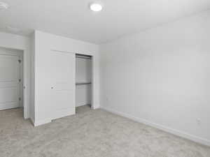 Unfurnished bedroom with light colored carpet and a closet