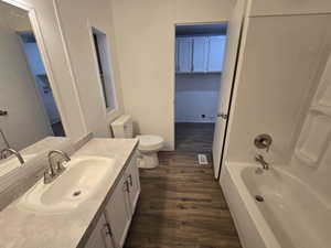 Full bathroom featuring hardwood / wood-style floors, vanity, toilet, and shower / washtub combination