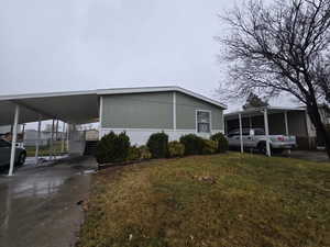 Manufactured / mobile home with a sunroom, a front yard, and a carport