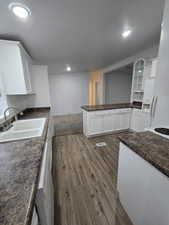 Kitchen with white cabinets, dark hardwood / wood-style floors, white appliances, and sink