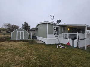 Back of property with a lawn and a storage unit