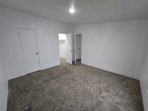 Unfurnished bedroom with dark colored carpet