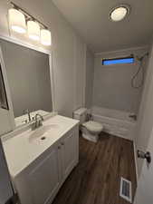 Full bathroom with hardwood / wood-style floors, vanity, toilet, and shower / washtub combination