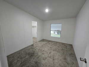 Carpeted empty room featuring vaulted ceiling