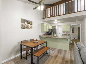 Dining area featuring a high ceiling, hardwood / wood-style flooring, ceiling fan, and sink