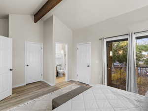 Bedroom featuring access to exterior, ensuite bathroom, light hardwood / wood-style flooring, high vaulted ceiling, and beamed ceiling