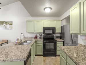 Kitchen with kitchen peninsula, sink, green cabinetry, and black appliances