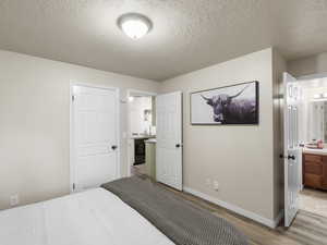 Bedroom featuring connected bathroom, a textured ceiling, and light wood-type flooring