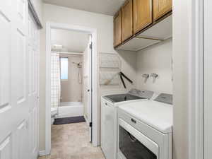 Washroom with separate washer and dryer, cabinets, and a textured ceiling