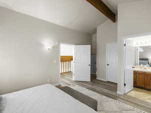 Bedroom with ensuite bathroom, sink, high vaulted ceiling, beamed ceiling, and light hardwood / wood-style floors