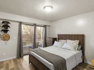 Bedroom featuring access to exterior, wood-type flooring, and a textured ceiling