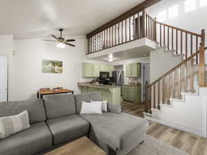 Living room featuring ceiling fan, high vaulted ceiling, and wood-type flooring