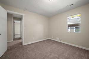 Carpeted empty room featuring a textured ceiling