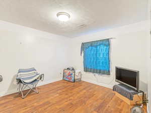 Miscellaneous room with wood-type flooring and a textured ceiling