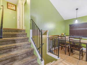 Stairs with tile patterned flooring and high vaulted ceiling