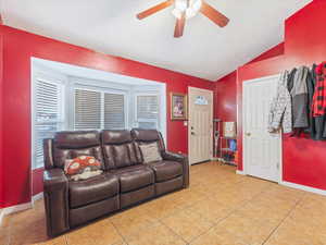 Tiled living room featuring ceiling fan and lofted ceiling