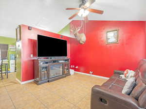 Tiled living room featuring ceiling fan and vaulted ceiling