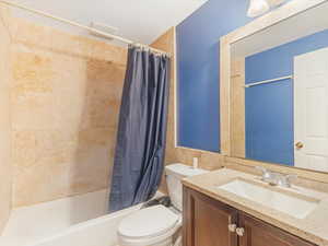 Full bathroom with vanity, toilet, and shower / bath combo with shower curtain