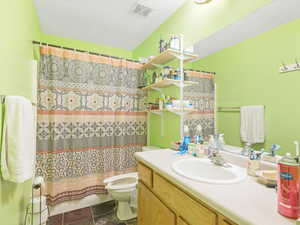 Bathroom featuring a shower with curtain, vanity, and toilet