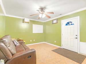 Tiled entryway featuring ceiling fan and ornamental molding