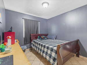 Bedroom with light tile patterned floors and a textured ceiling