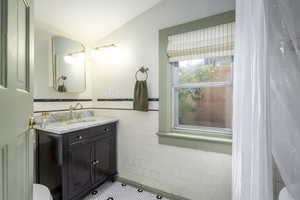 Bathroom with tile patterned floors, lofted ceiling, vanity, and tile walls