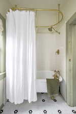 Bathroom featuring tile patterned floors, shower / bathtub combination with curtain, and tile walls