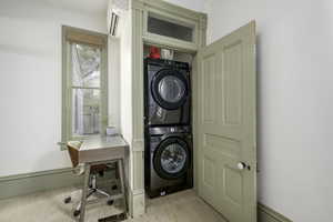 Laundry area with a wall unit AC, light hardwood / wood-style flooring, and stacked washer / drying machine